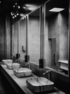 Sleek and modern public restroom with marble sinks and large mirrors in black and white.